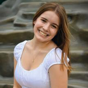 Sara Weller smiling tilting her head wearing a white dress.