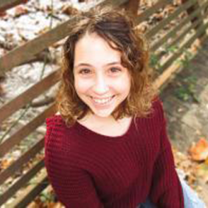 Syd Casterline in a red sweater with a fence in the background.