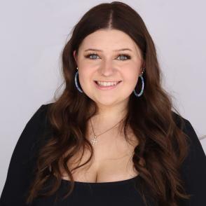 An image of Lucy Becker in a black shirt and light blue pants, in front of a white background.