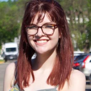 Alyssa Embry smiles at the camera wearing glasses