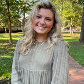 Brooke Klopfenstein smiles with a slightly tilted head, wearing a sage green blouse