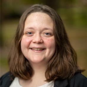 Faith Laughlin smiles at the camera, wearing a white shirt and black jacket