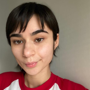 Gabriela Grijalva smiles at the camera, wearing a white and red baseball shirt and smiles at the camera in a selfie photo.