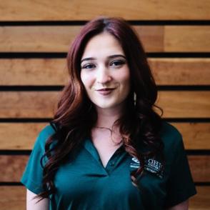 Lexi Jones smiles at the camera, wearing an Ohio University Housing and Residence Life polo shirt.