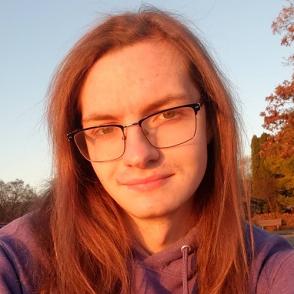 Luvina Cooley smiles at the camera in a golden hour selfie, wearing glasses and a purple hoodie