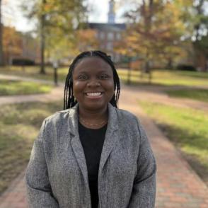 Jandè Thomas stands on College Green and smiles at the camera with her hands in front of her