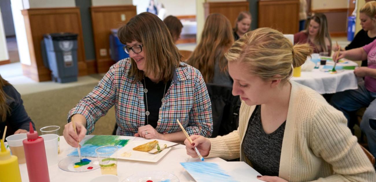 A parent and student painting together.