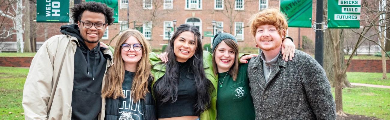 Group of 5 people standing on College Green smiling.