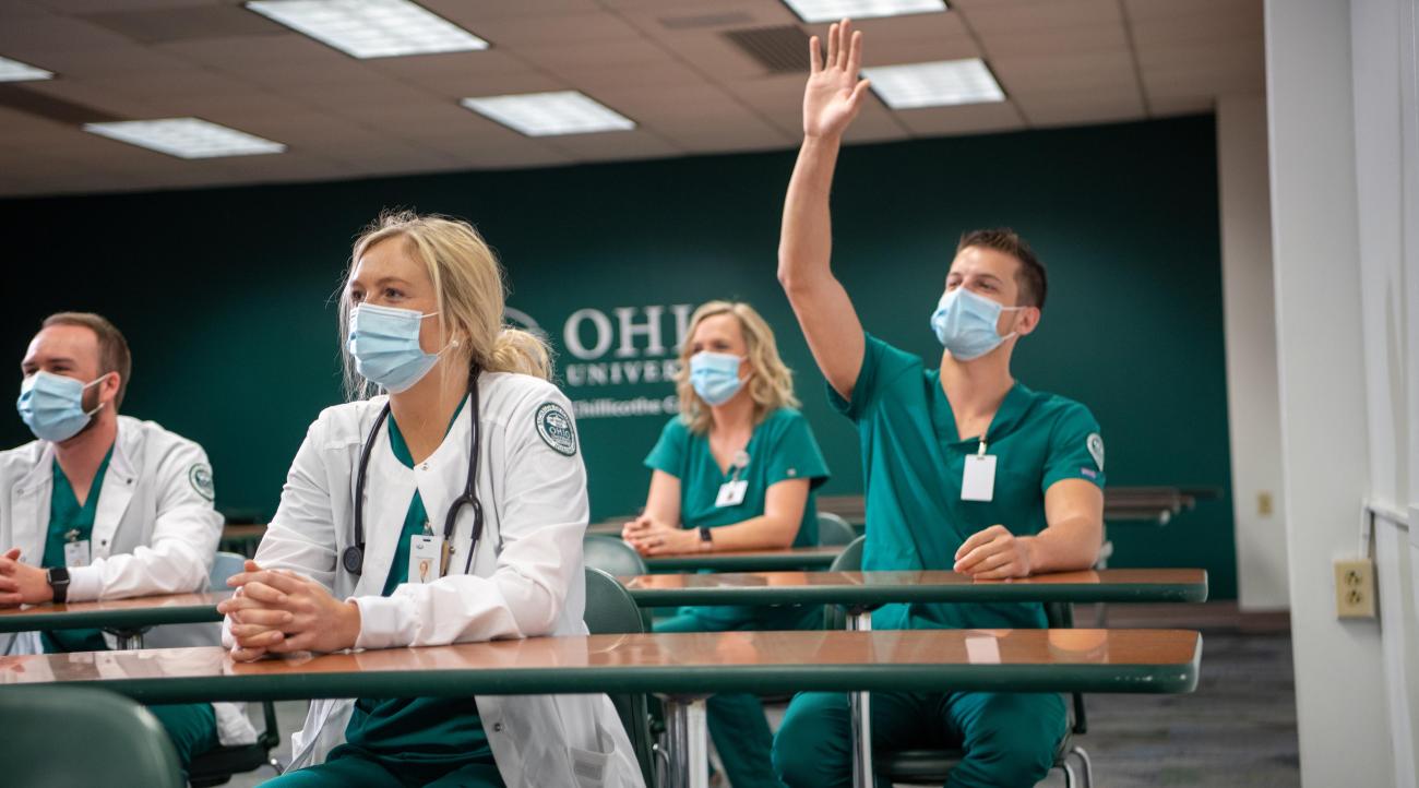 group of students sit in a nursing lecture, one student has his hand raised
