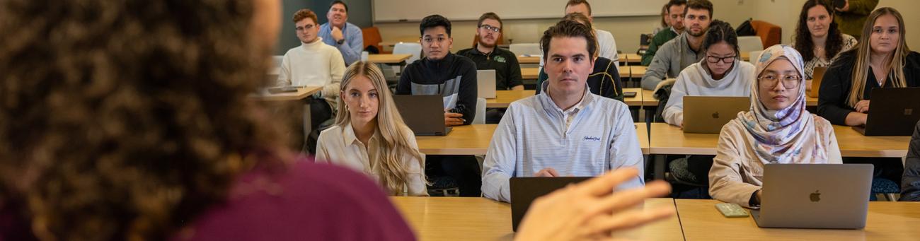 A teacher stands in front of a classroom teaching students.