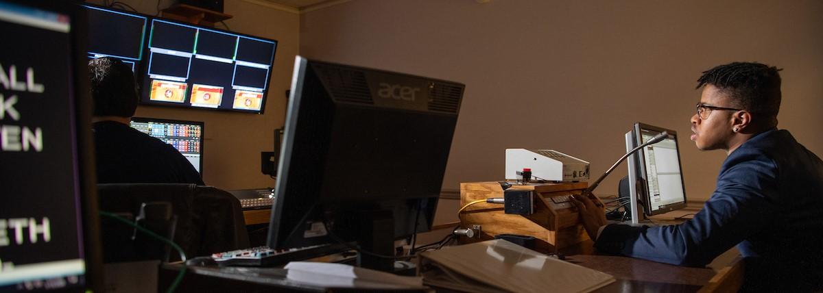 A student uses a microphone in a computer lab. 
