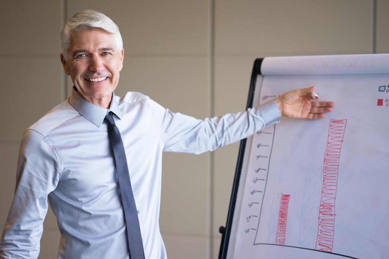 Older man explaining data from a chart. Image by Freepik.