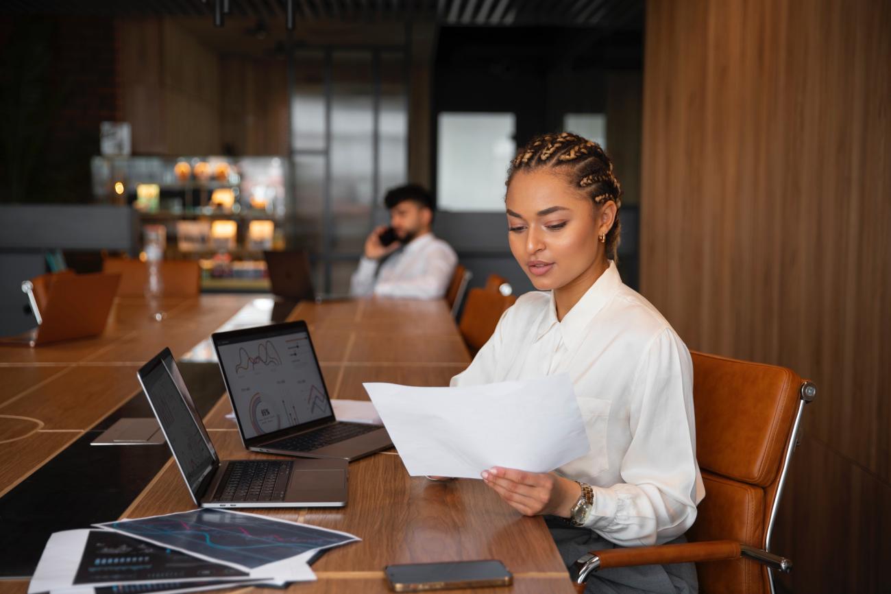 Finance worker looking at graphs and computer. Image by Freepik.