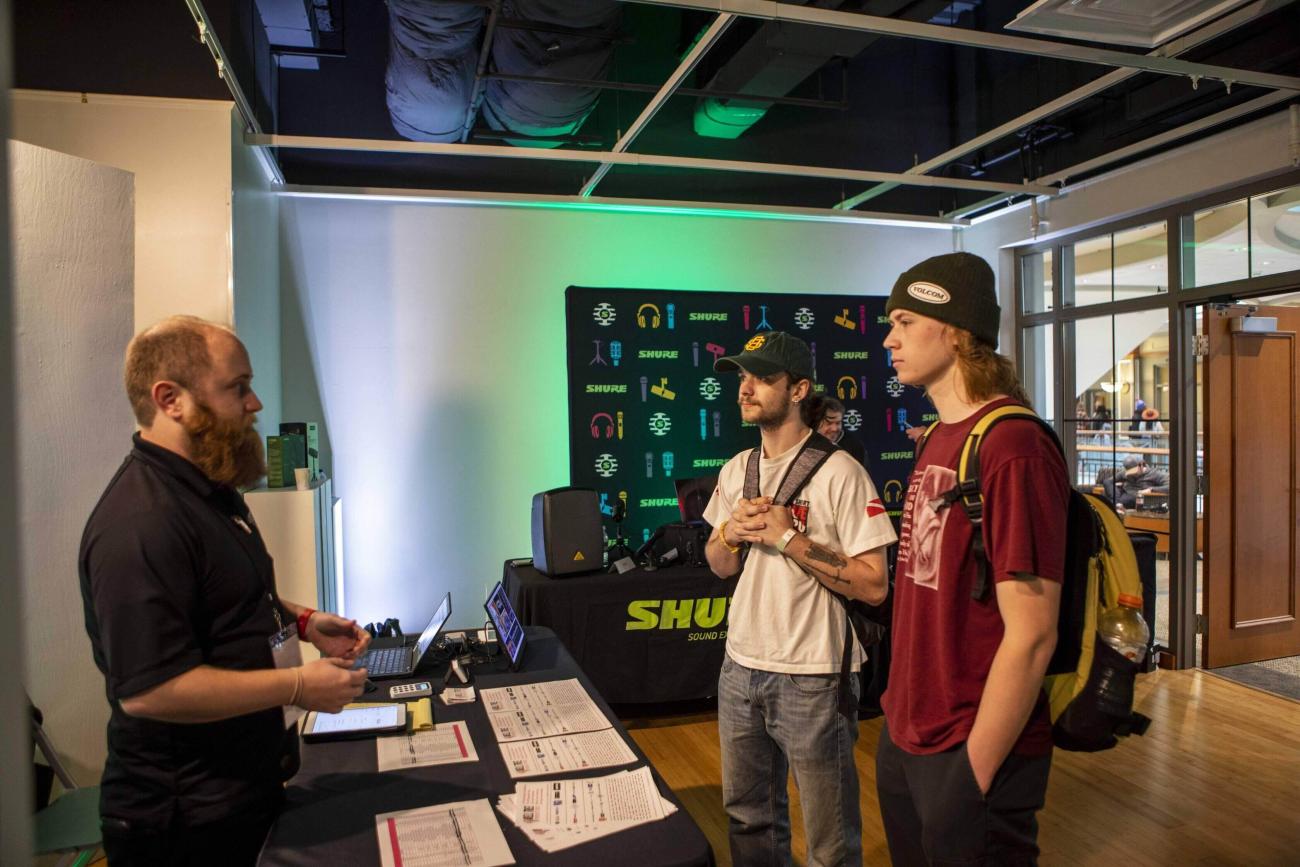Two students talk to a company representative at Expo