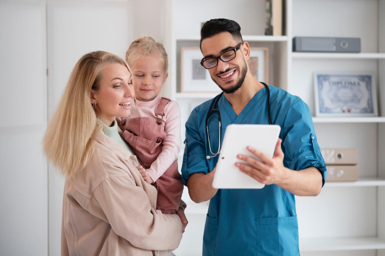Male nurse speaking to mother and child. Image by Freepik.