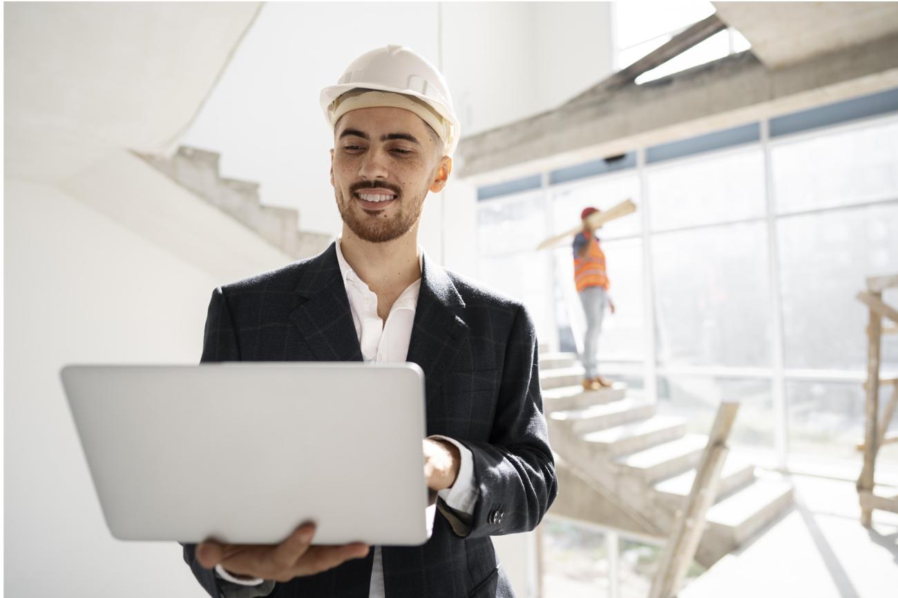 An engineer checks his computer at a job site. Image by Freepik.
