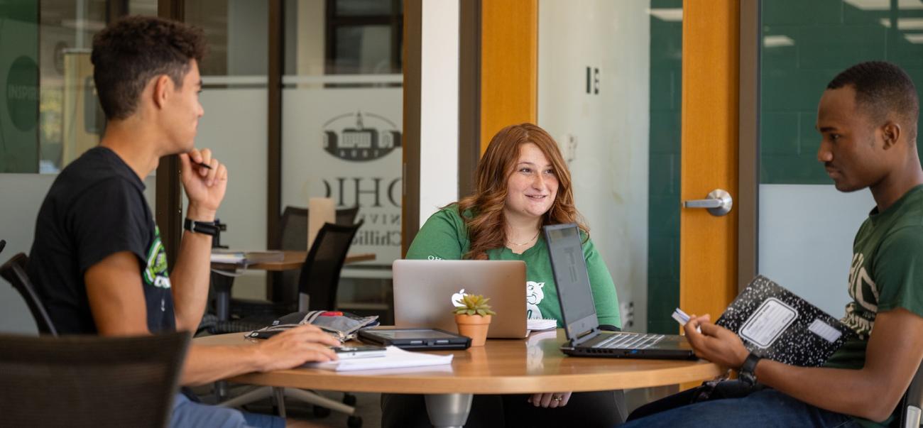 three students gather around a table in the student success center