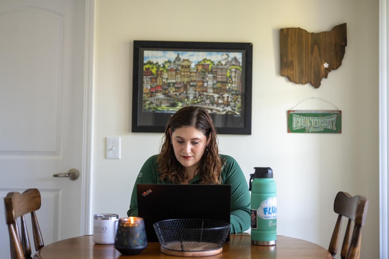 woman sits at laptop in her house