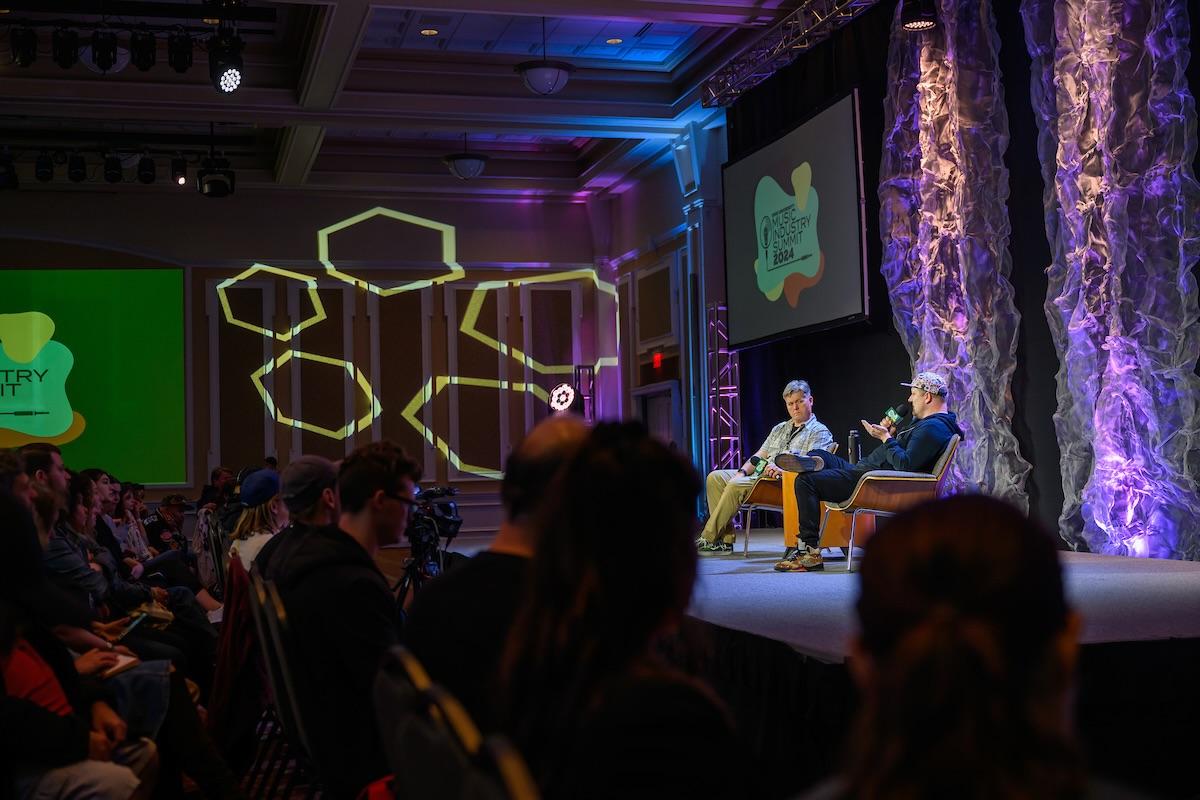 Two panelists talking on stage with audience in foreground