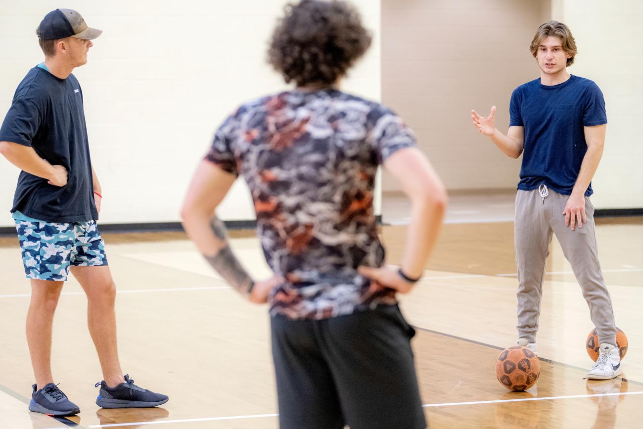 Three people standing on a basketball court