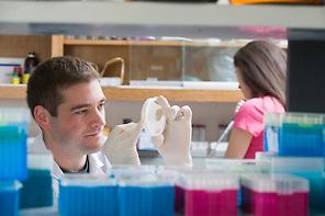 Two students perform experiments within a lab