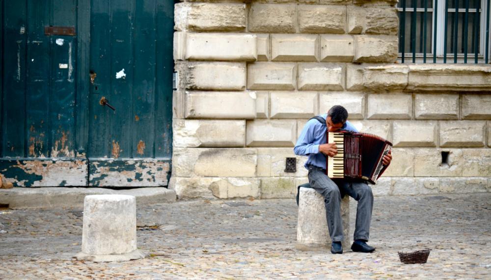 A person playing an accordion in front of a brick wall. 