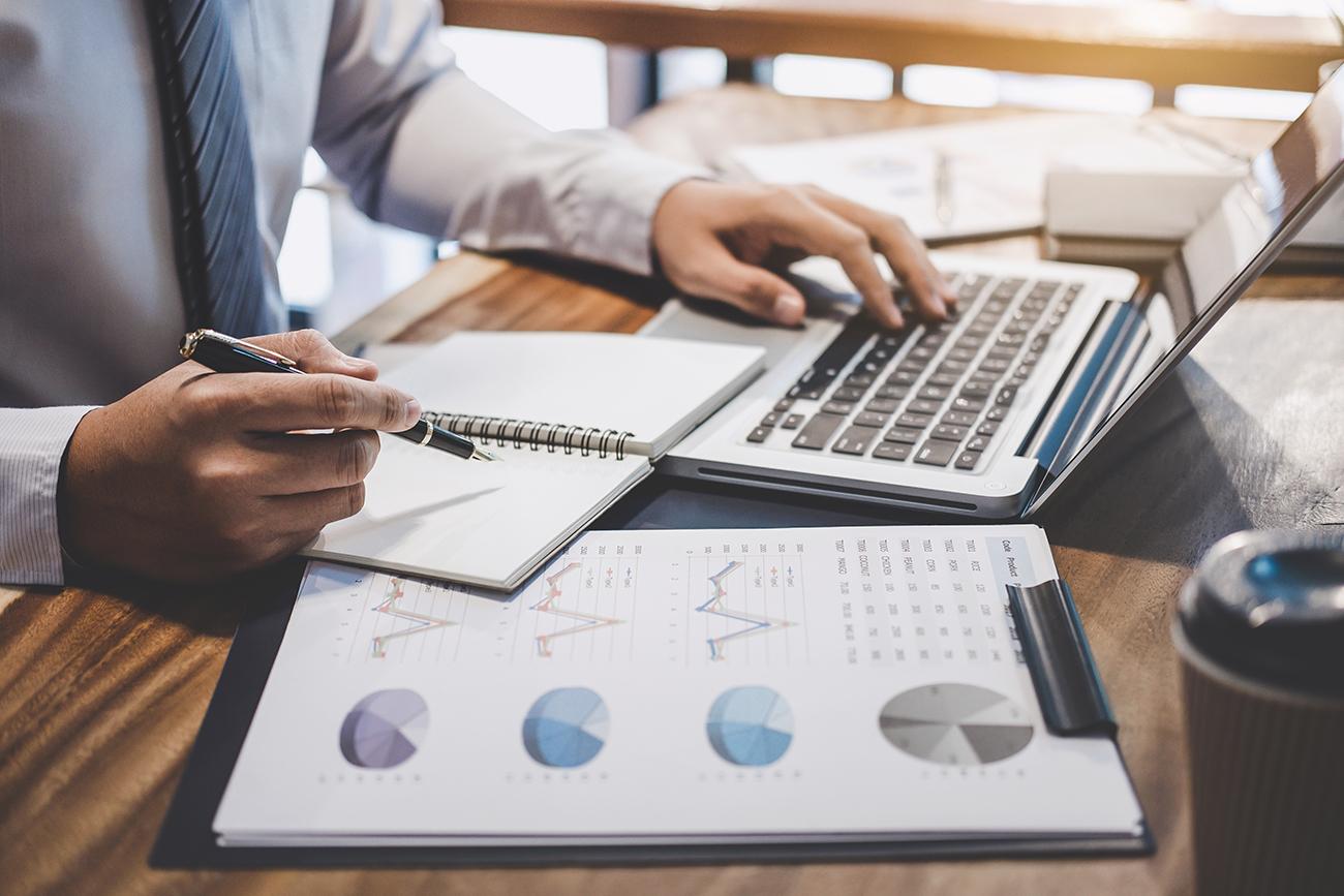 Person working on a computer with data reports in front of them