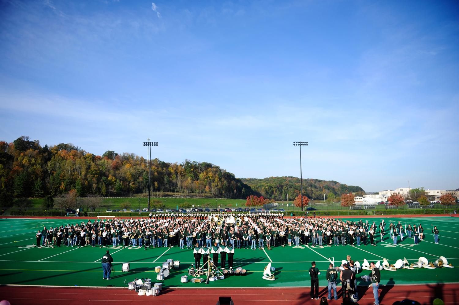 Marching 110 alumni play their instruments on the field