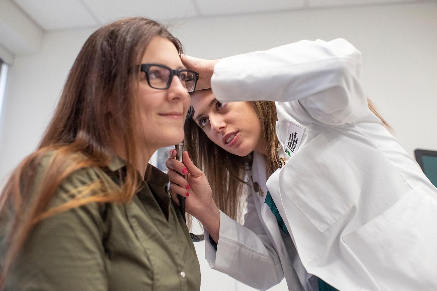 Osteopathic medical student looks in a patient's ear