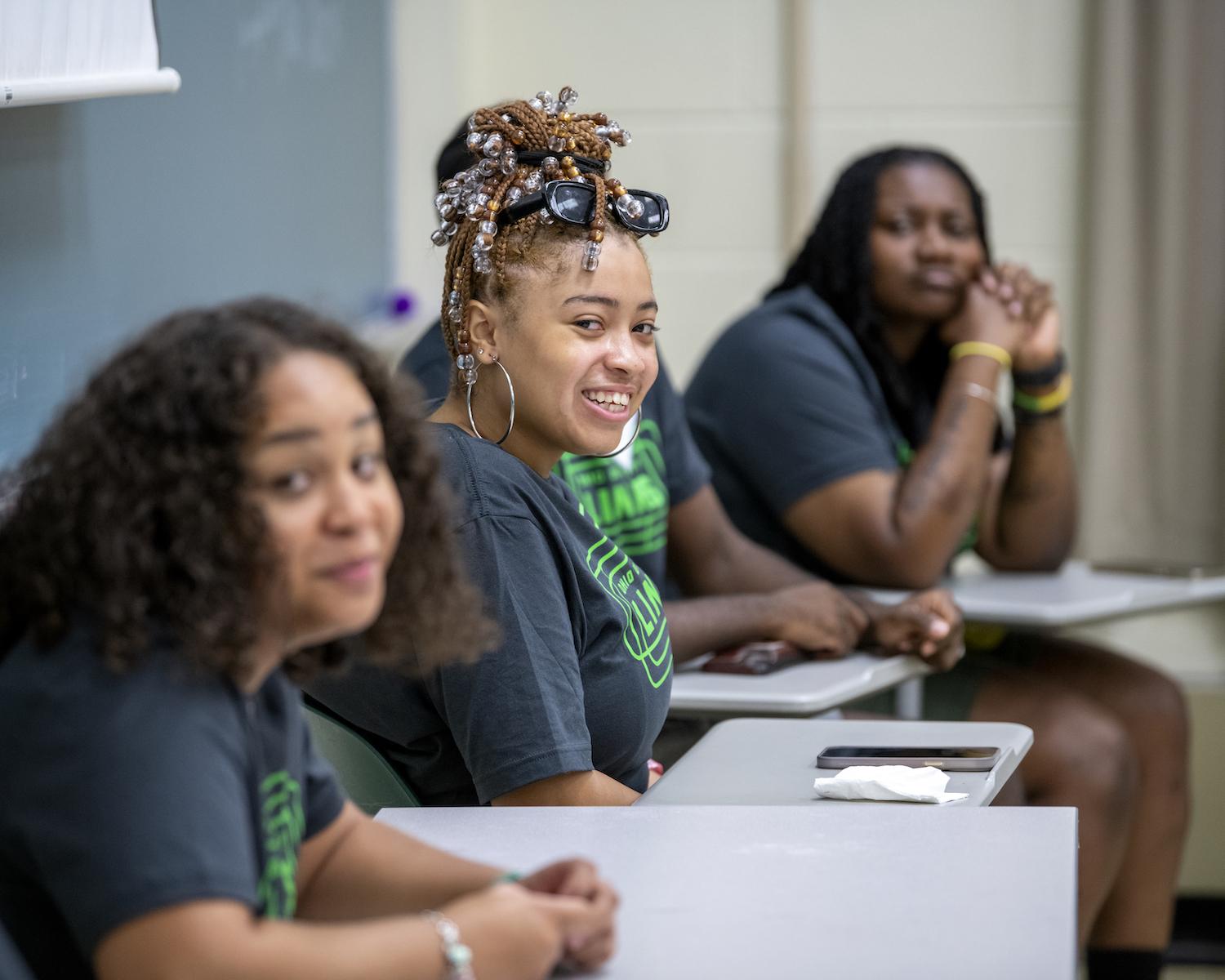 A LINKS student smiles at their desk 