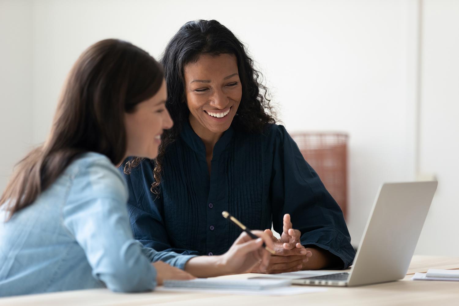 Woman helping another woman use a laptop