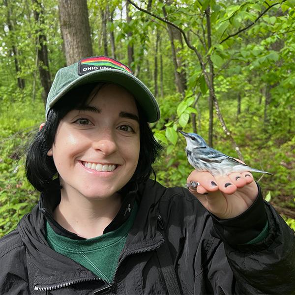 A conservation student holds a bird.