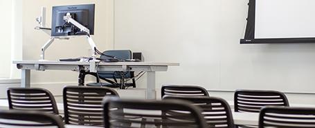 Classroom inside Ellis Hall, with tables and chairs, with a computer and presentation setup at the front of the room