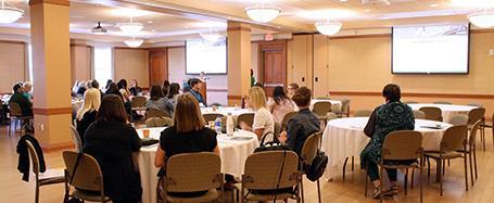 Baker Center 240-242 expanded fully, with round tables and chairs set up for a presentation at front of room