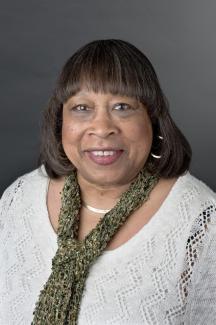 Headshot of woman in white sweater with green scarf.