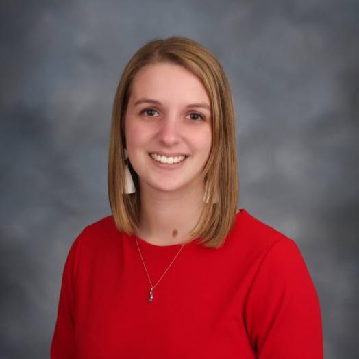 white woman in her twenties with dirty blonde hair, pretty smile, wearing a red blouse.