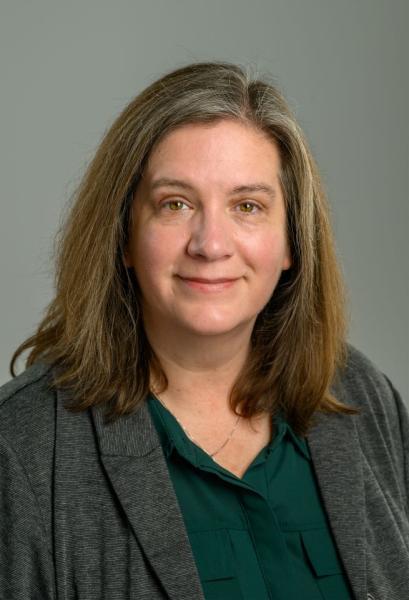 Katie Hartman shown from shoulder up. She is wearing a green shirt  and grey jacket