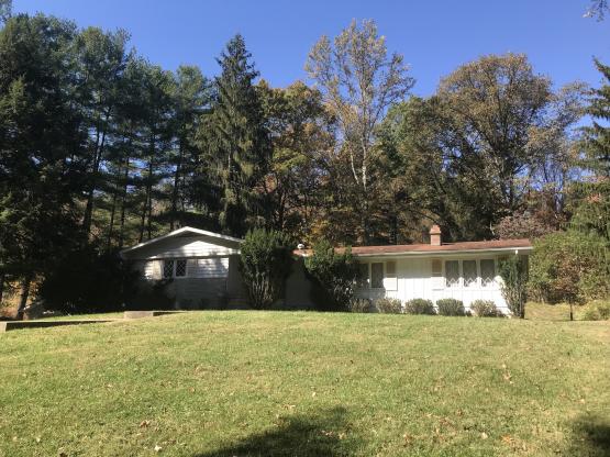 Ranch-style house with lawn in front and trees in back