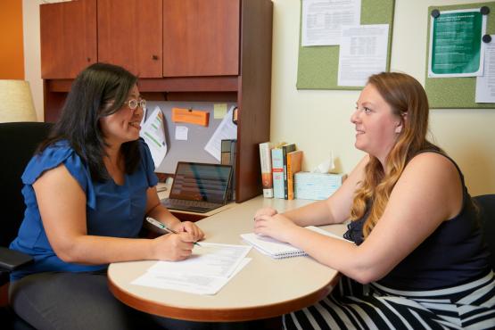 A staff member advises a student in their office.