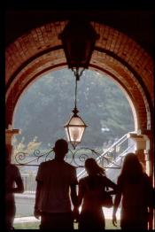 People in a walkway with an arch at the end