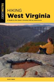 Woman sitting on rocks looking out at bridge.