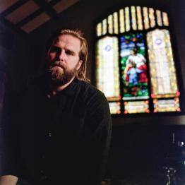 Charles Wesley Godwin headshot with stained glass window in background