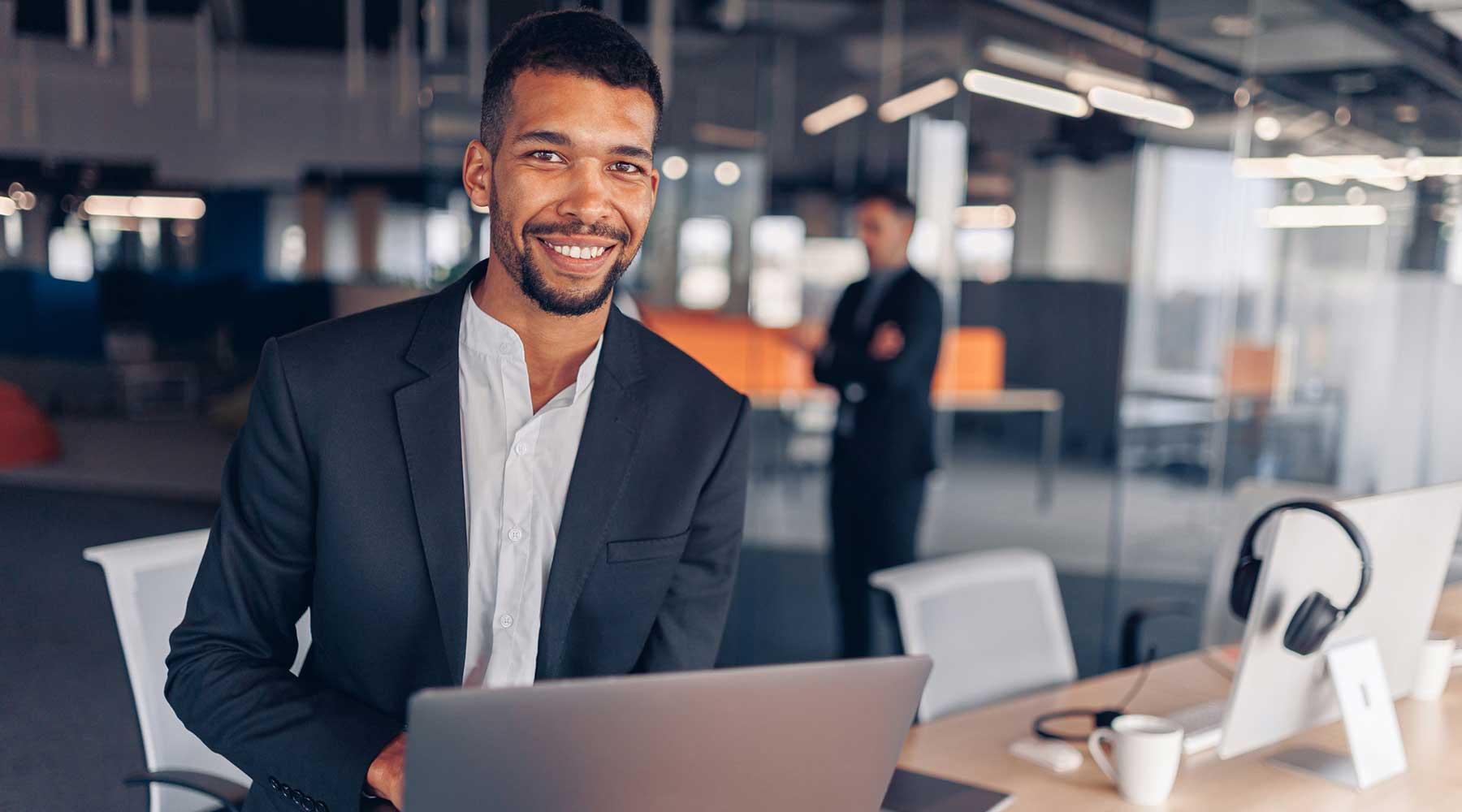 Engineer holding a laptop and smiling at camera