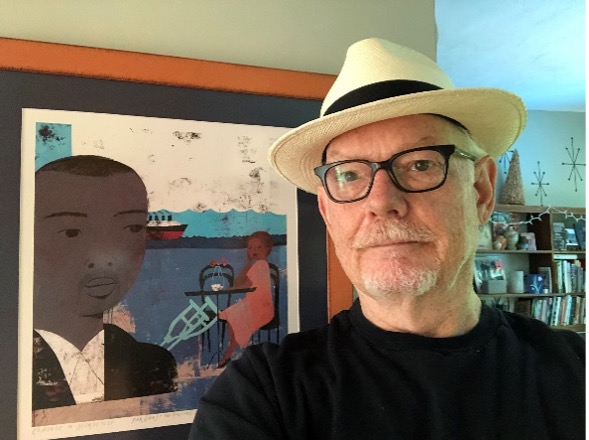 Gary Holcomb poses with a framed copy of the artwork for the novel "Romance in Marseille"