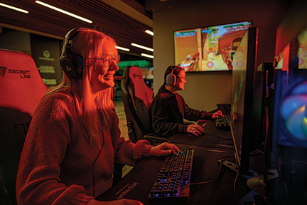 two female Ohio University students wearing videoconferencing headsets sit at computers in the OHIO 