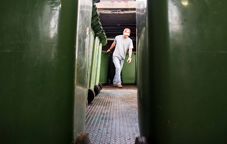 A Compost Facility worker moves a compost bin.