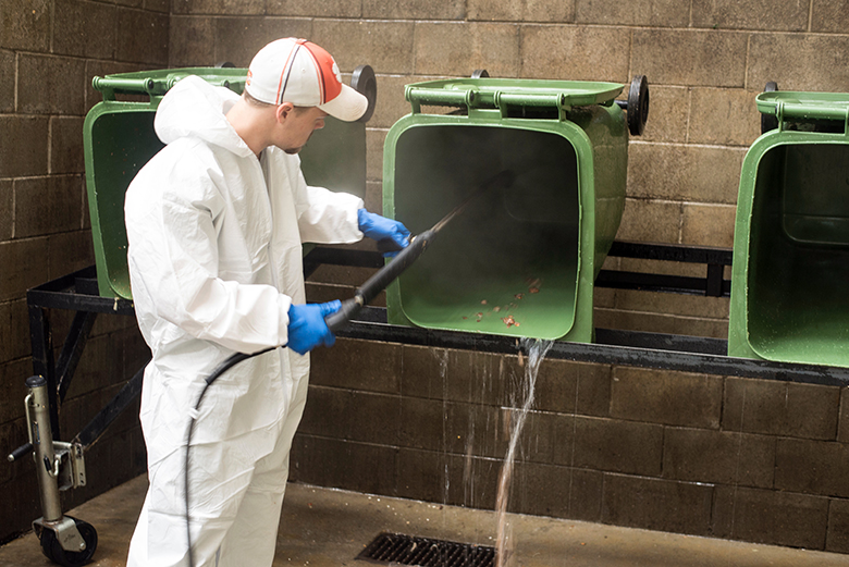 A Compost Facility worker power-washes the compost bins