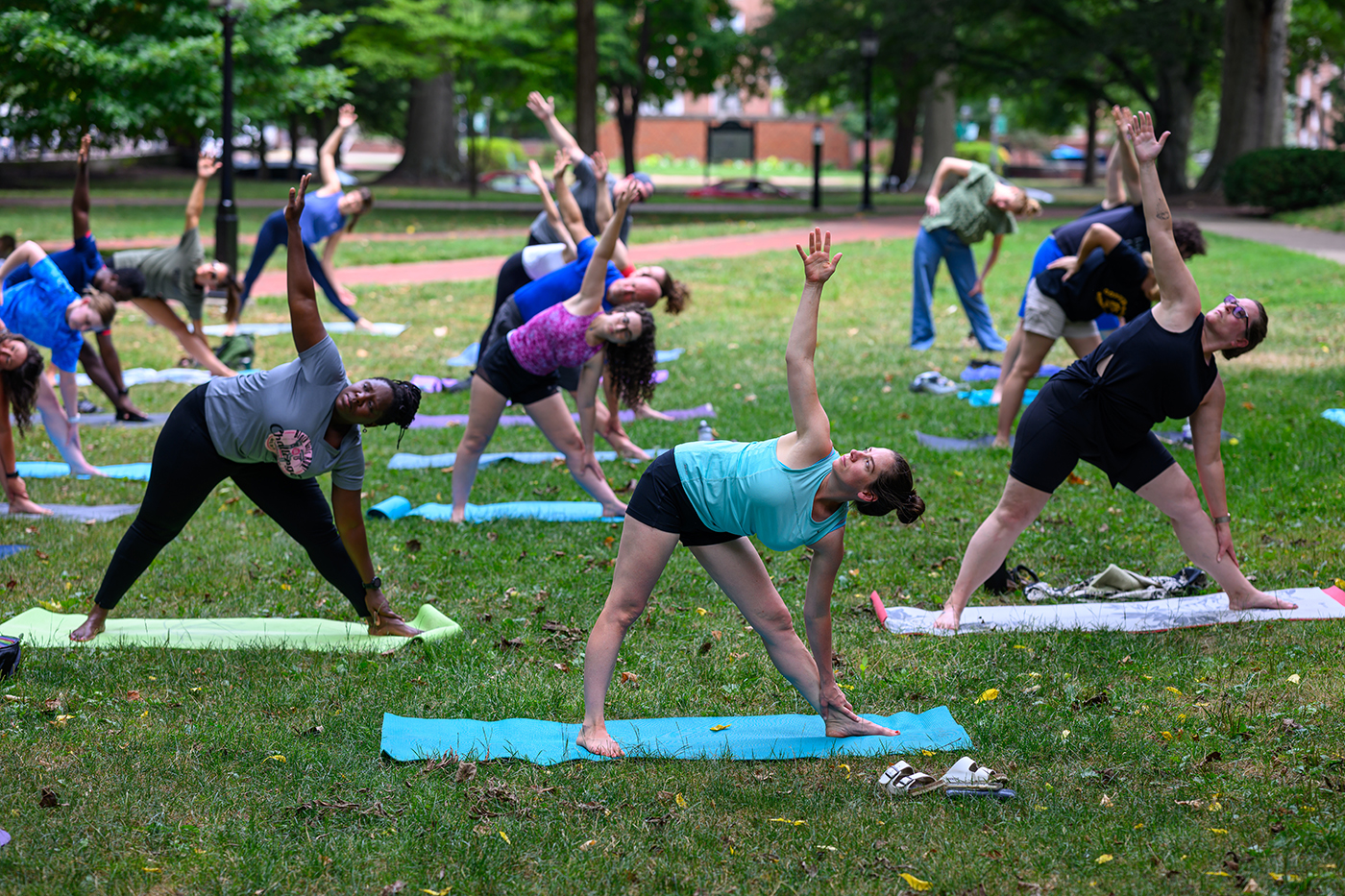 Participants do yoga on 大学绿色 in summer of 2024.