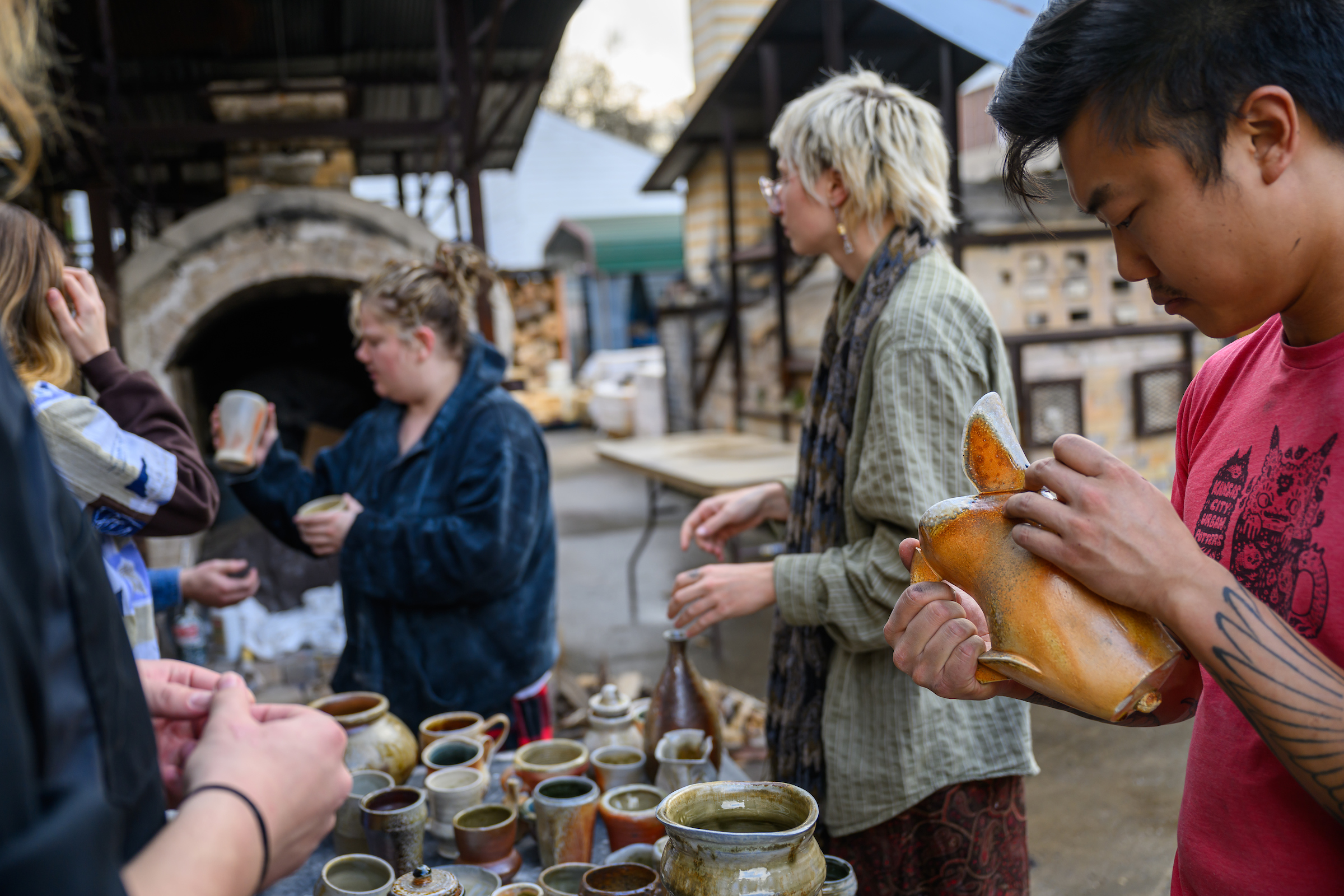 shoppers peruse ceramic pieces made by 俄亥俄大学 students and faculty in an outdoor kiln yard