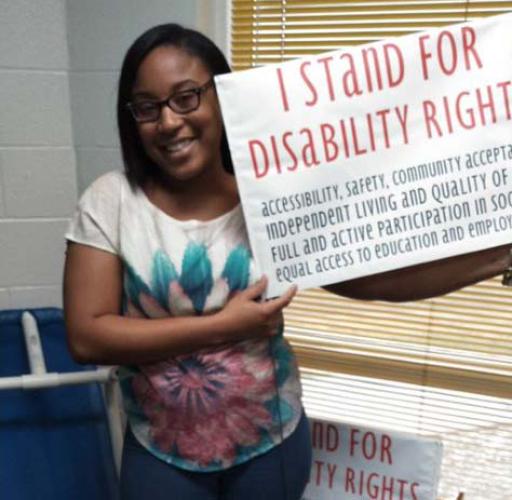 Tyaira Williams holding a sign that says "I stand for disability rights"